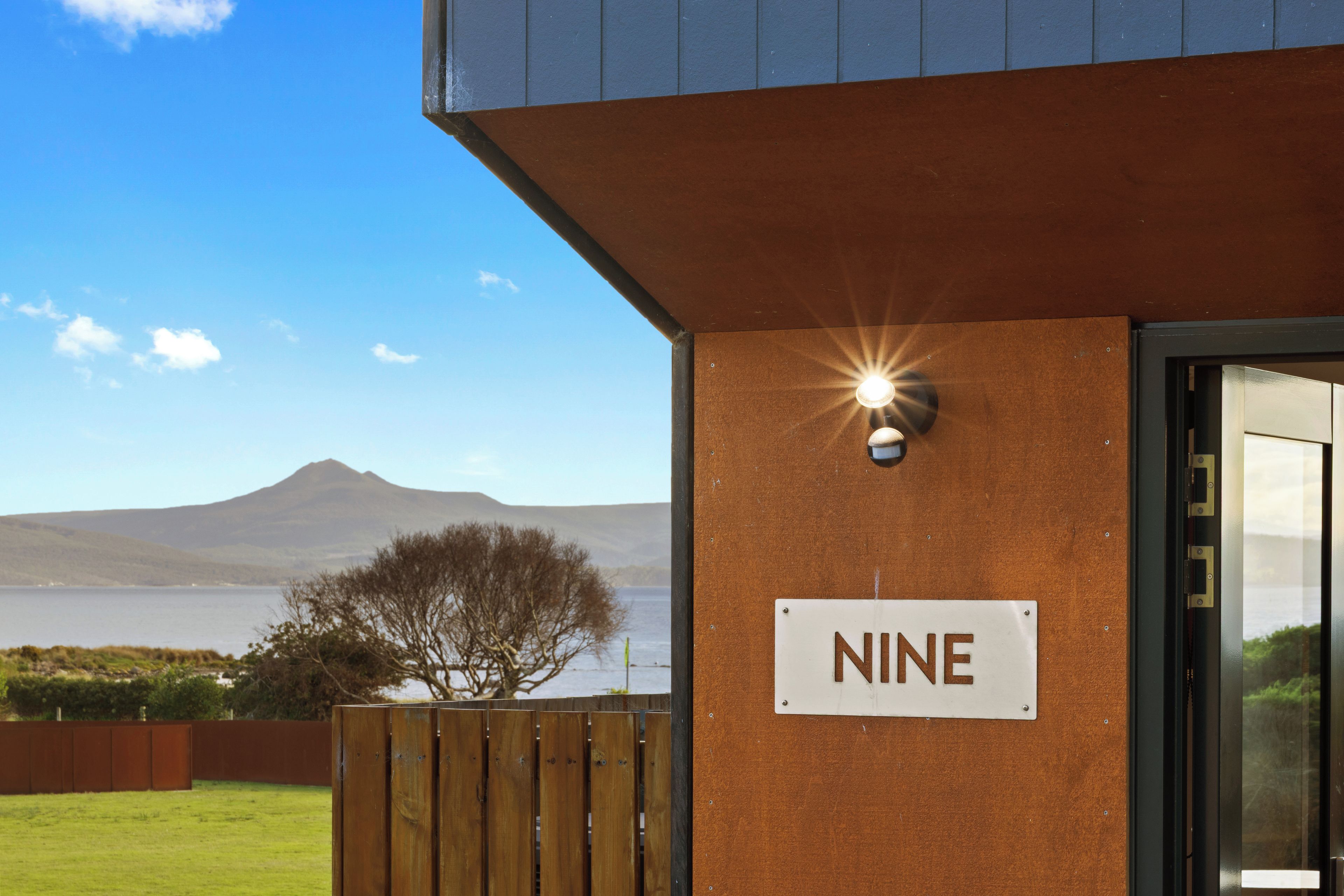 A building with a sign labeled 'NINE' and a view of a mountain and water body in the background.