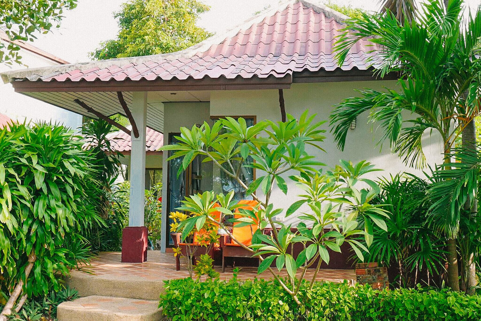 A house with a tiled roof, a covered porch, and a garden with various plants.