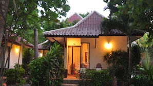 A traditional house with a tiled roof, surrounded by lush greenery and a stone pathway leading to the entrance. - Samui Honey Cottages Beach Resort (Koh Samui)