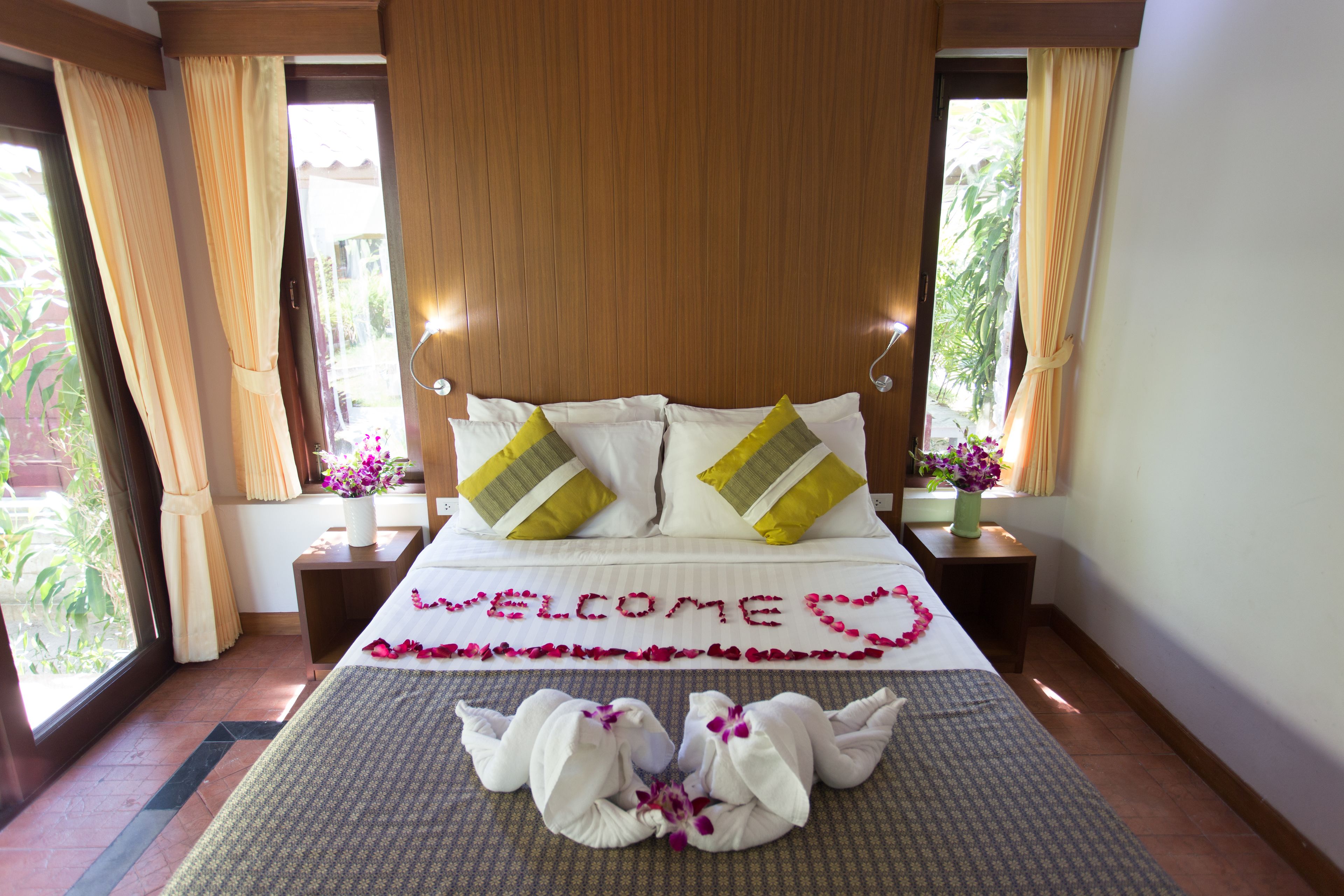 A hotel room with a bed, a welcome mat, and a view of the outdoors.