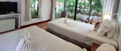 A hotel room with two beds, a TV, and large windows with curtains.