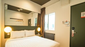 A hotel room with a large bed, bedside lamps, a mirror, a window with curtains, a door with a lock, and a thermostat on the wall. - Tune Hotel KLIA Aeropolis (Sepang)