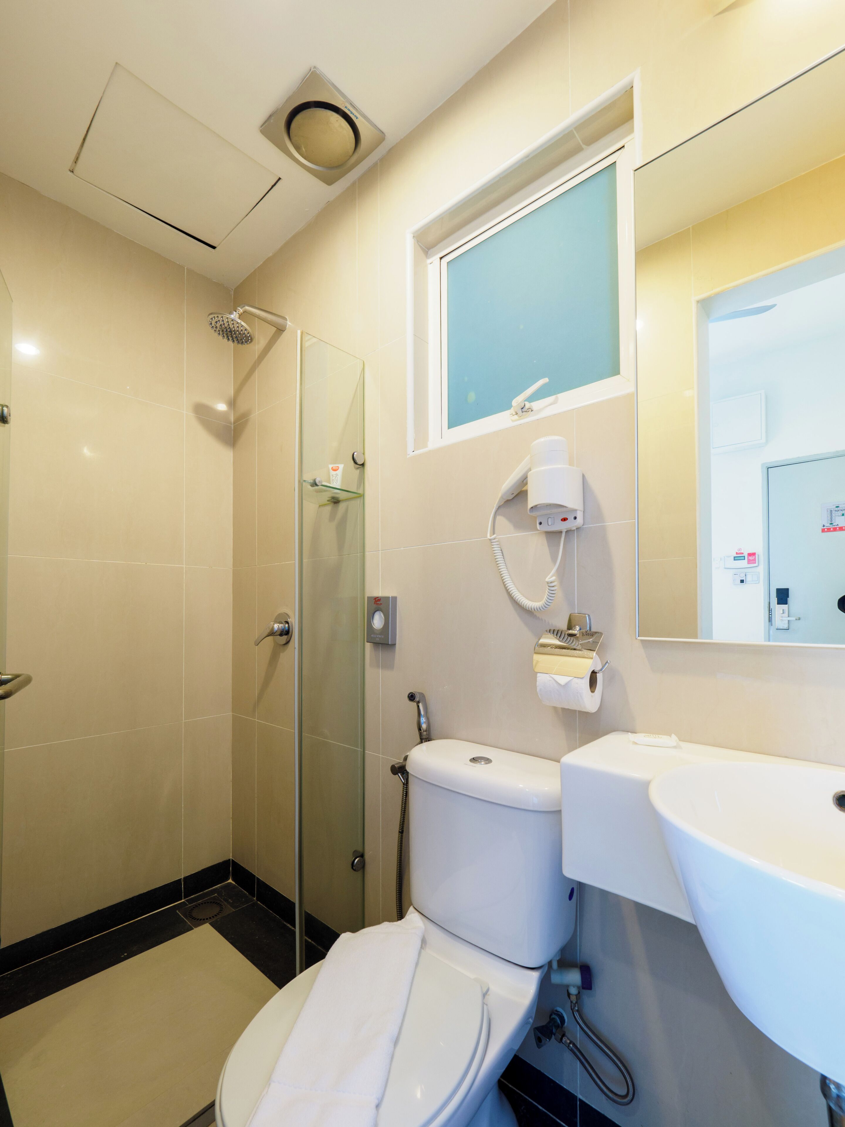 A modern bathroom with a glass-enclosed shower, a white toilet, and a sink with a mirror above it.