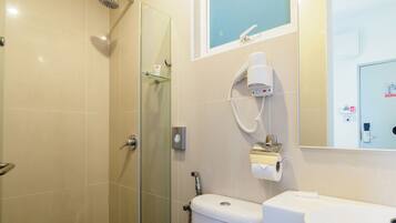 A modern bathroom with a glass-enclosed shower, a white toilet, and a sink with a mirror above it.