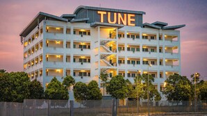 A multi-story hotel with a prominent 'TUNE' sign on the top, multiple balconies, and a central staircase. - Tune Hotel KLIA Aeropolis (Sepang)