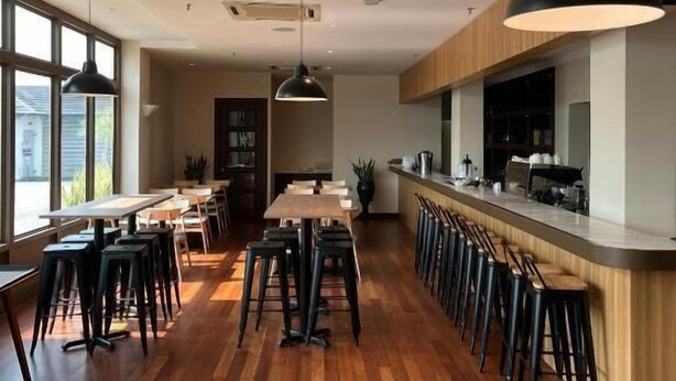 A modern restaurant with wooden flooring, black bar stools, and pendant lighting. - Tune Hotel KLIA Aeropolis (Sepang)