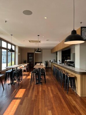 A modern restaurant with wooden flooring, black bar stools, and pendant lighting. - Tune Hotel KLIA Aeropolis (Sepang)