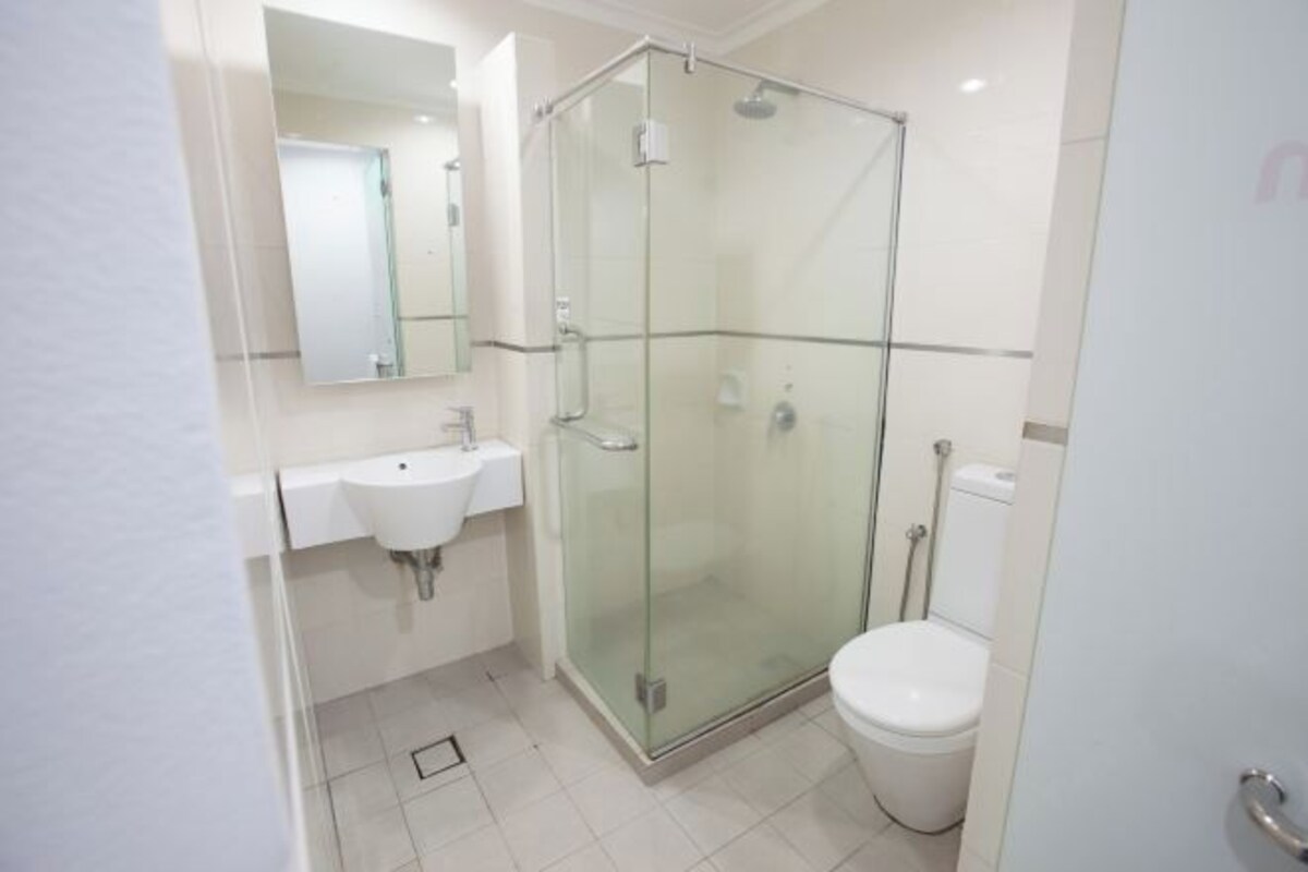 Un baño pequeño con cabina de ducha de vidrio, un lavabo blanco y un inodoro.