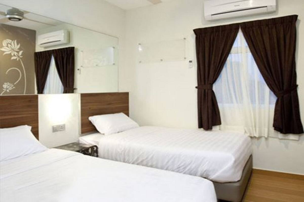 A hotel room with two beds, a wooden headboard, an air conditioning unit, a mirror, and a window with brown curtains.