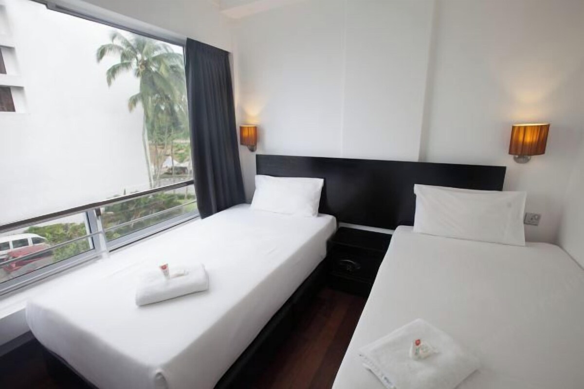 Habitación de hotel con dos camas, un ventanal grande y vistas a palmeras.