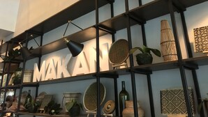 A modern interior with a black metal shelving unit displaying various decorative items and a large sign with the word "MAKAI". - Tune Hotels - 1 Borneo, Kota Kinabalu (Kota Kinabalu)