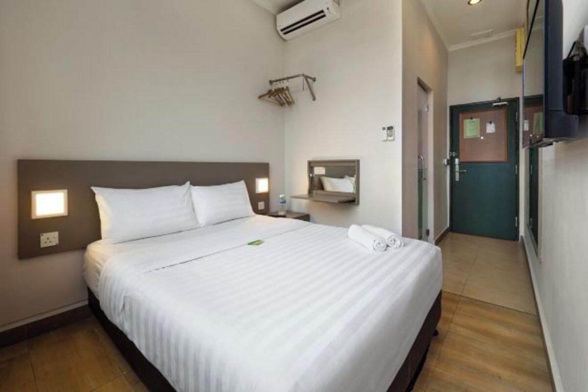 Ett hotellrum med en säng, sängbord, en luftkonditioneringsanläggning, en spegel och en dörr.