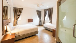 A hotel room with two beds, a ceiling fan, a large mirror, and a glass shower door. - NIO Hotel (George Town)