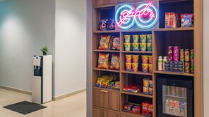 A snack vending machine and a neon sign in a hallway. - NIO Hotel (George Town)