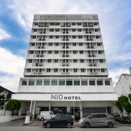 A multi-story hotel with balconies, a clear sky, and a sign reading 'NIO HOTEL'.