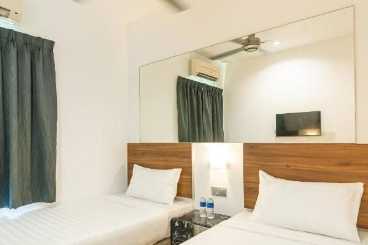 Une chambre d’hôtel avec deux lits, un ventilateur de plafond, un appareil de climatisation, une table de chevet avec une lampe et un grand miroir au mur.