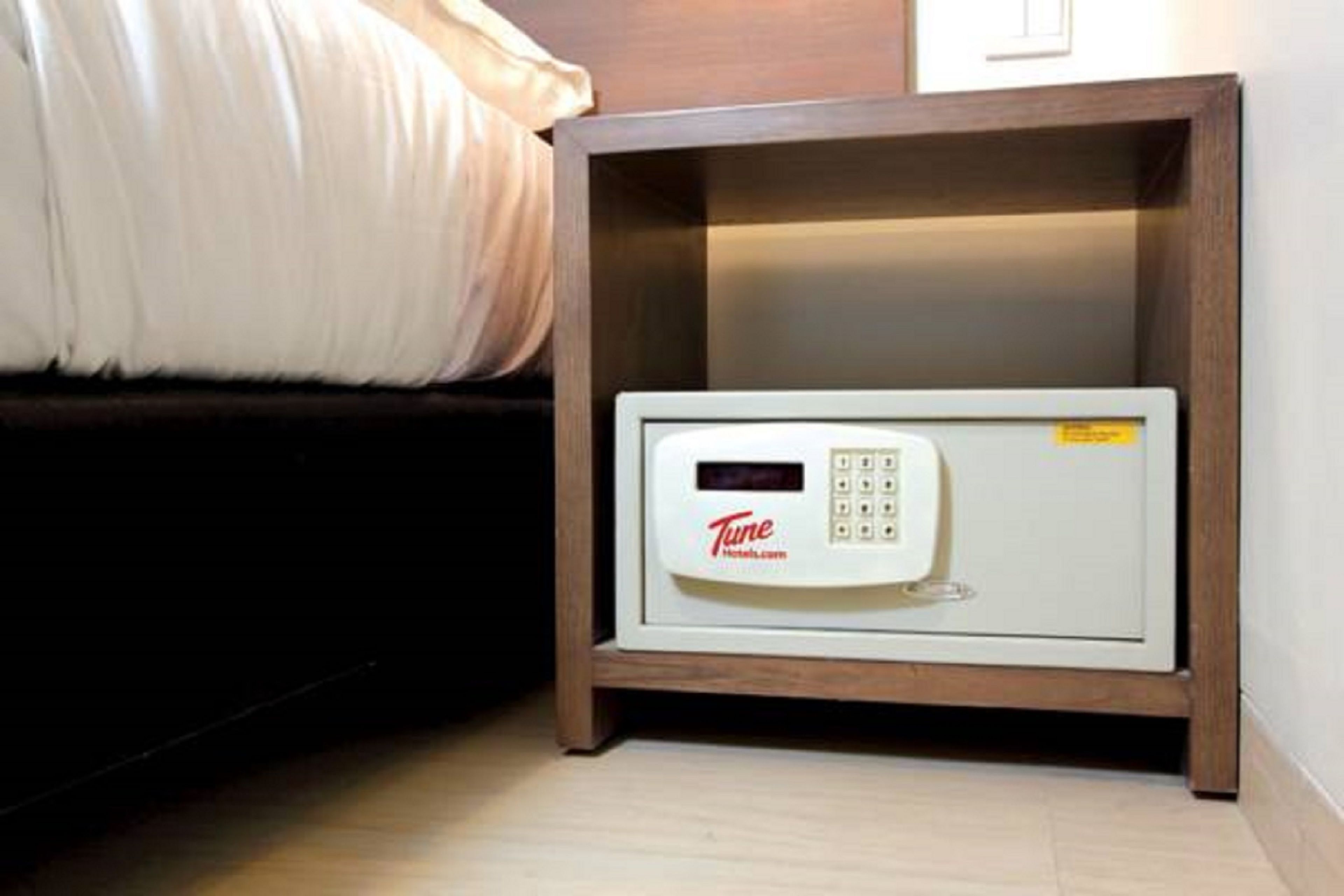 A Tune hotel room with a microwave on a wooden shelf.