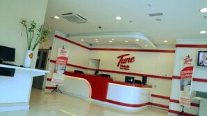 A Tune Hotel reception area with a modern design, featuring a red and white color scheme, a reception desk, and a large wall-mounted sign. - Tune Hotels - Kota Bharu City Centre (Kota Bharu)