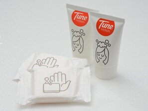 Zwei Flaschen Tune Hotels Handdesinfektionsmittel und eine Packung Feuchttücher.