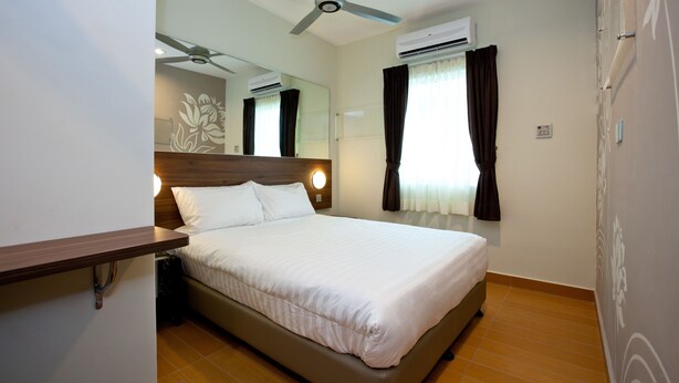 A hotel room with a bed, a ceiling fan, an air conditioning unit, a mirror, and a window with curtains. - Tune Hotels - Kota Bharu City Centre (Kota Bharu)