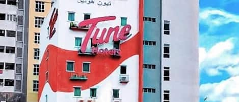 Un edificio de varios pisos con un letrero llamativo de 'Tune Hotels'.