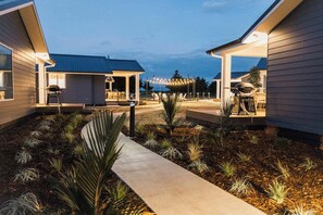 A modern outdoor patio area with a concrete pathway, seating, and barbecue equipment. - Tasman Holiday Parks - Miranda (Miranda)