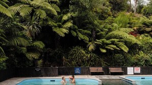 En swimmingpool omgivet af frodig vegetation, med et skilt der viser den varmeste ende.