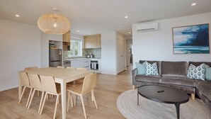 En moderne opholdsstue med spiseplads, køkken og et hyggeligt siddeområde med sofa og sofabord.