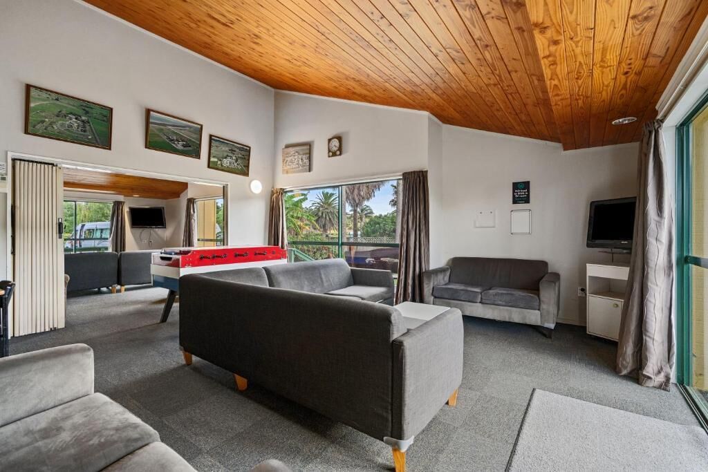 A modern living room with a pool table, sofas, and a television.