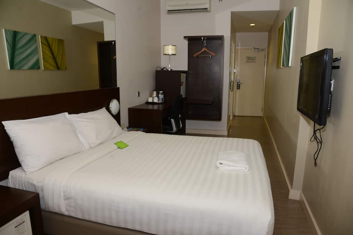 Una habitación de hotel con cama, escritorio, televisor y armario.
