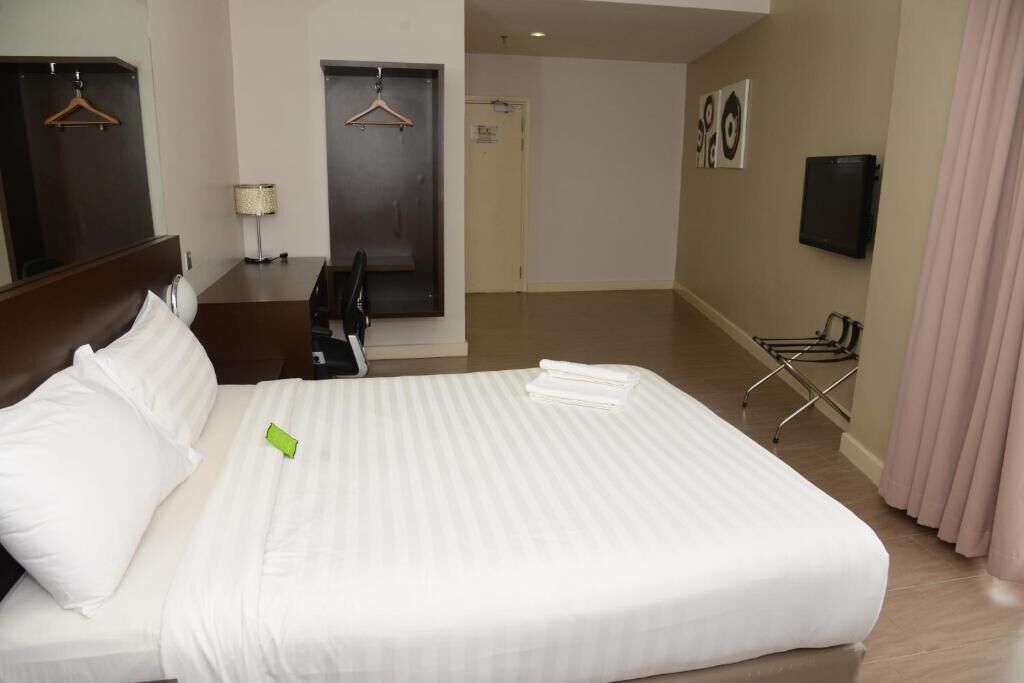 Una habitación de hotel con una cama grande, un escritorio, una silla, un televisor y una puerta.