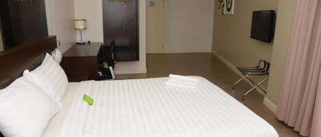Una habitación de hotel con una cama grande, un escritorio, una silla, un televisor y una puerta.