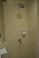 Un baño con ducha, inodoro y dispensador de jabón en la pared.
