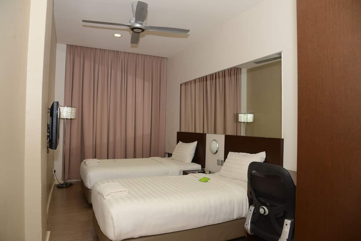 Habitación de hotel con dos camas, ventilador de techo, televisor de pantalla plana y un espejo grande.