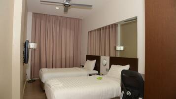 Habitación de hotel con dos camas, ventilador de techo, televisor de pantalla plana y un espejo grande.
