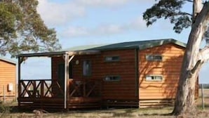 A wooden cabin with a porch, a door, and a window.