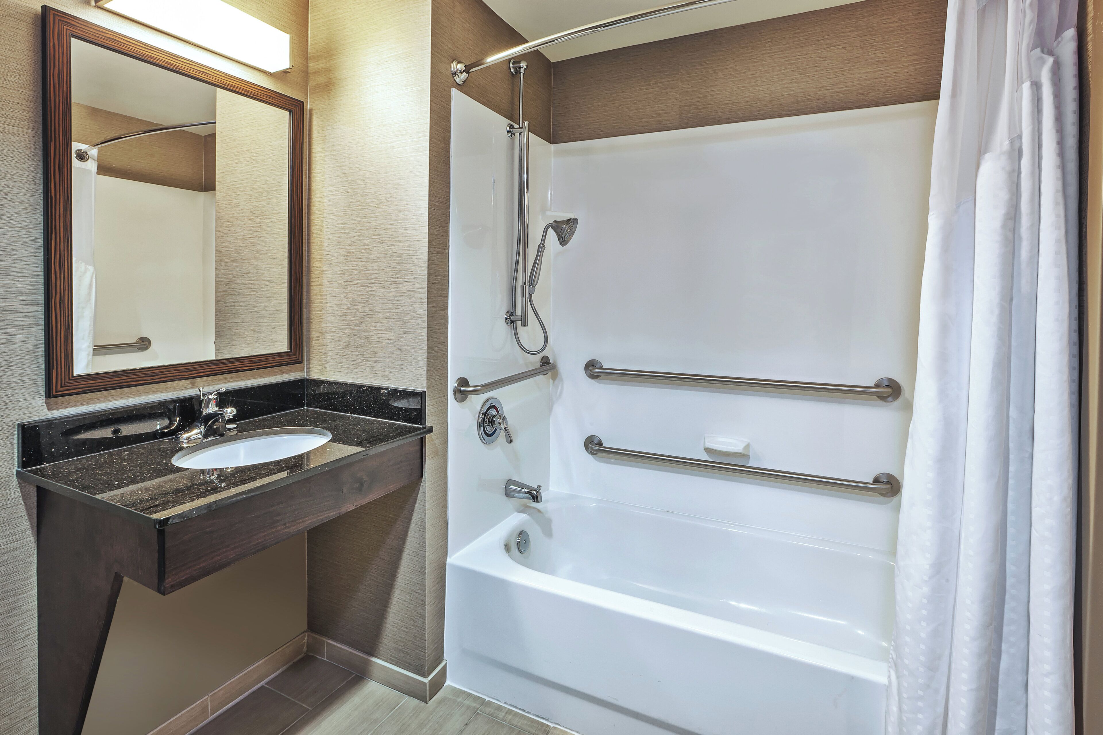 Un baño con lavamanos, espejo, ducha y bañera.