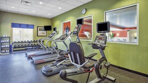 Une salle de sport équipée de plusieurs tapis de course, de machines de musculation et d’haltères.