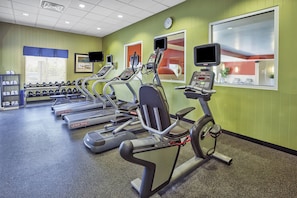 Ein Fitnessstudio mit mehreren Laufbändern, Kraftgeräten und Kurzhanteln.