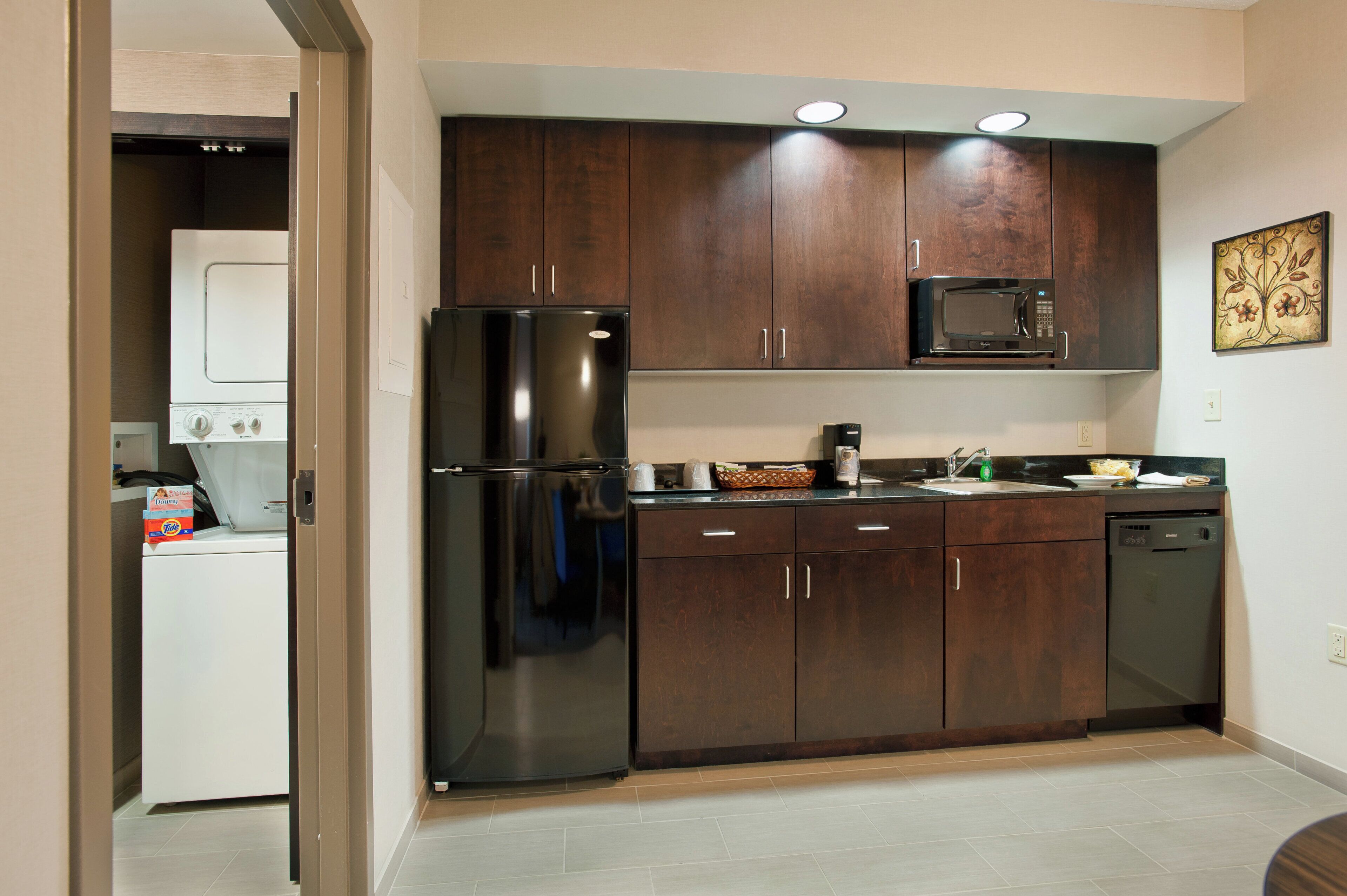Una cocina moderna con armarios de madera oscura, un refrigerador de acero inoxidable, un microondas y un lavavajillas.