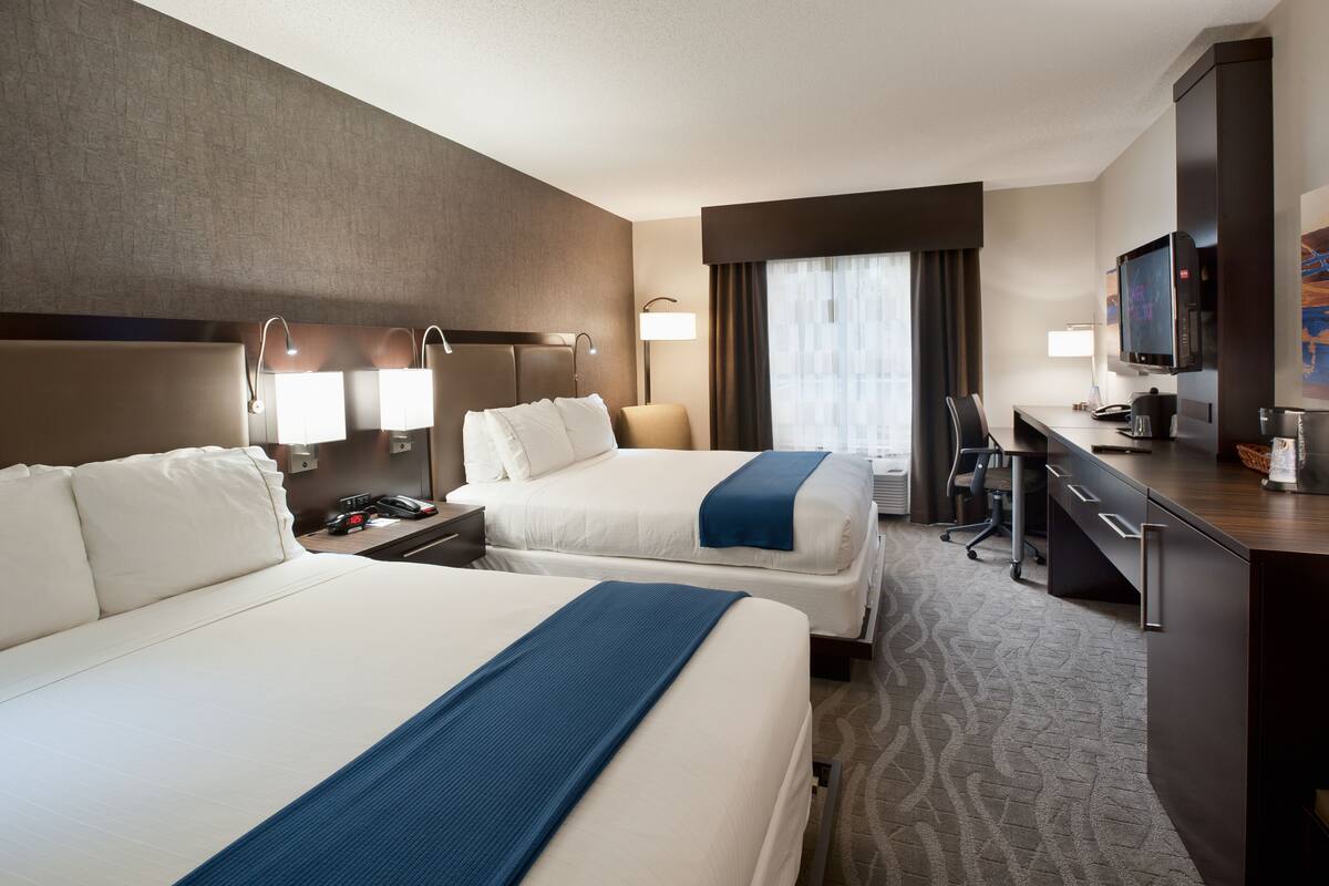 Una habitación de hotel con dos camas, un escritorio, un televisor y un minibar.