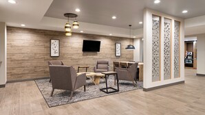 A modern lobby with a wooden wall, a flat-screen TV, and a seating area with chairs and a table. - Candlewood Suites Chambersburg by IHG (Chambersburg)