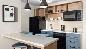 A modern kitchen with a central island, black appliances, and blue cabinetry. - Candlewood Suites Chambersburg by IHG (Chambersburg)