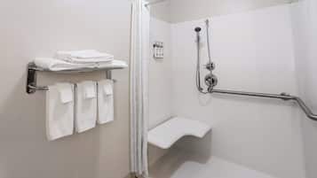 A modern bathroom with a walk-in shower, a towel rack with folded towels, and a shower control panel.