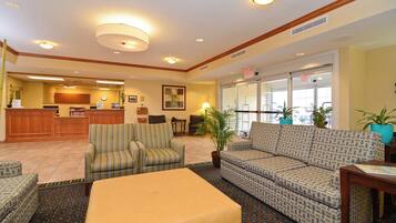 A hotel lobby with a reception desk, seating area, and exit signs.
