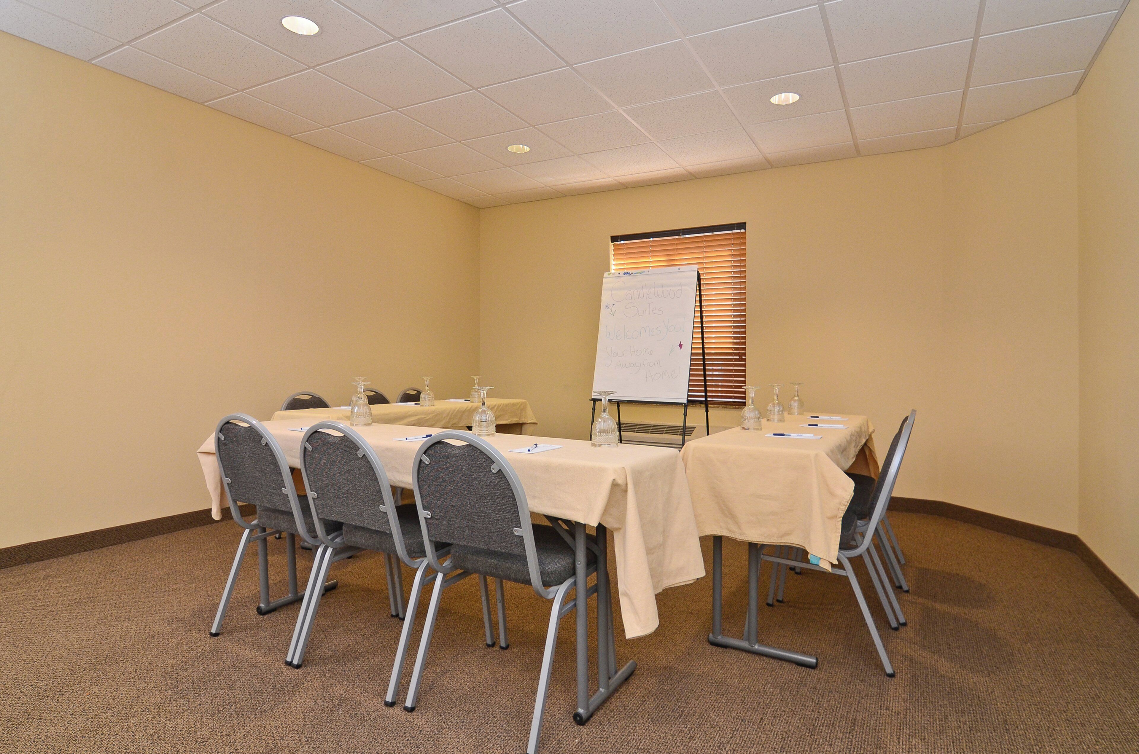 A conference room with a whiteboard, tables, chairs, and a carpeted floor.