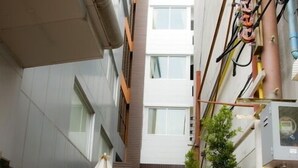 A narrow alleyway with outdoor seating, a potted plant, and a building with multiple windows and balconies. - Buddy Boutique Inn (Bangkok)