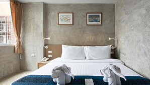 A hotel room with a large bed, two framed artworks on the wall, a bedside table with a lamp, and a window with curtains. - Buddy Boutique Inn (Bangkok)