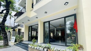 A modern hotel entrance with a glass door, potted plants, and a signboard. - Windbell Villa (Da Nang)