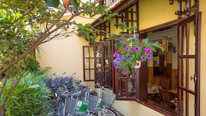 A bicycle parked outside a building with a yellow wall and wooden shutters. - Windbell Villa (Da Nang)